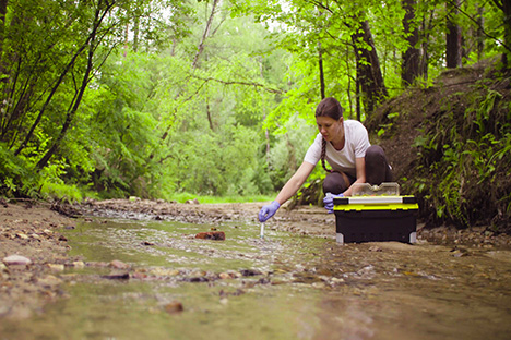 Una mujer científica estudiando el nivel de sal en un río para determinar cómo contribuye la sal en el calentamiento global. 