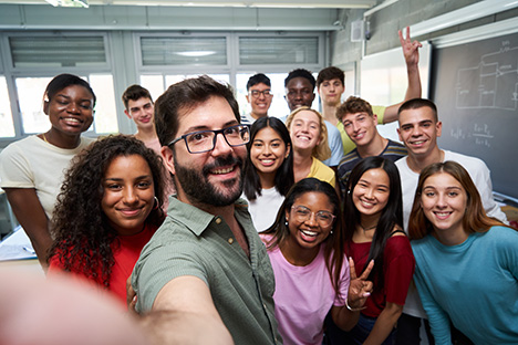 Un grupo de estudiantes jóvenes tomándose una foto con su profesor para celebrar la inclusión. 