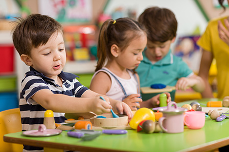 Un grupo de niños jugando en clases con juguetes de cocina sin importar su género para impulsar la igualdad.  