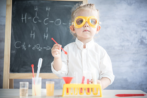 Una niña realizando un experimento científico en su salón de clase. 