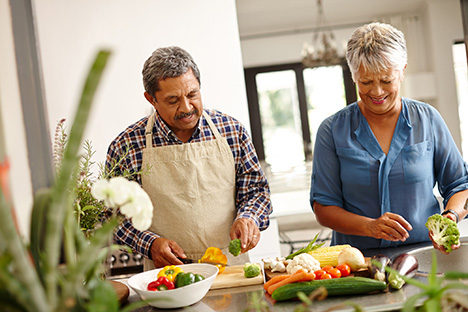 Dos personas mayores preparando alimentos saludables.