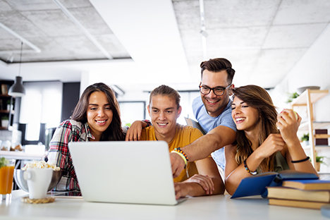 Un grupo de estudiantes reunidos alrededor de una computadora, trabajando en equipo. 