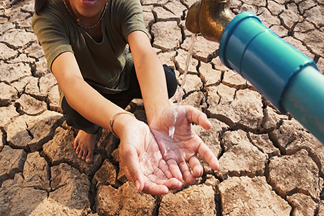 Una personas recibiendo agua potable en sus manos.