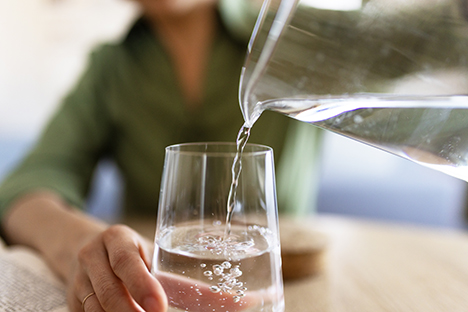 Una señora sirviéndose un vaso de agua pura.  