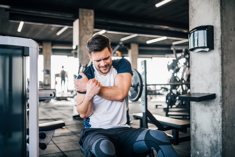 Un deportista con dolor de hombro después de practicar entrenamiento de fuerza. 