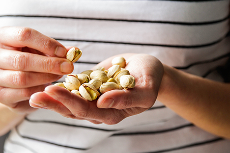 Una persona consumiendo pistachos para mejorar su salud ocular. 