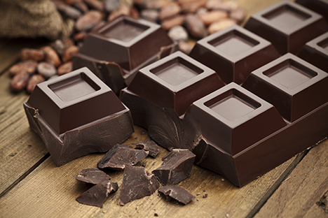 Trozos de chocolate negro sobre una mesa de madera. 