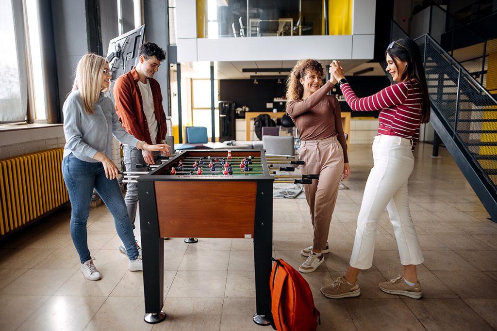 Diseño inclusivo empresarial: Empleados jugando en una mesa de futbolín.