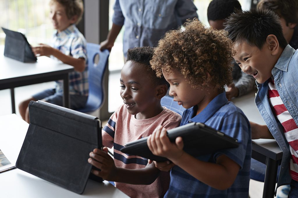 Tres chicos utilizan sus tablets en el aula